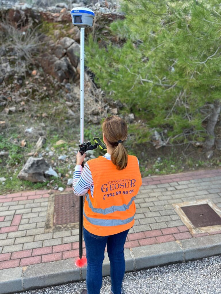 Topógrafa de Geosur realizando medición con equipo GPS en un área urbana en Málaga